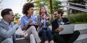 A group of four employees enjoying a laugh outside during lunch.