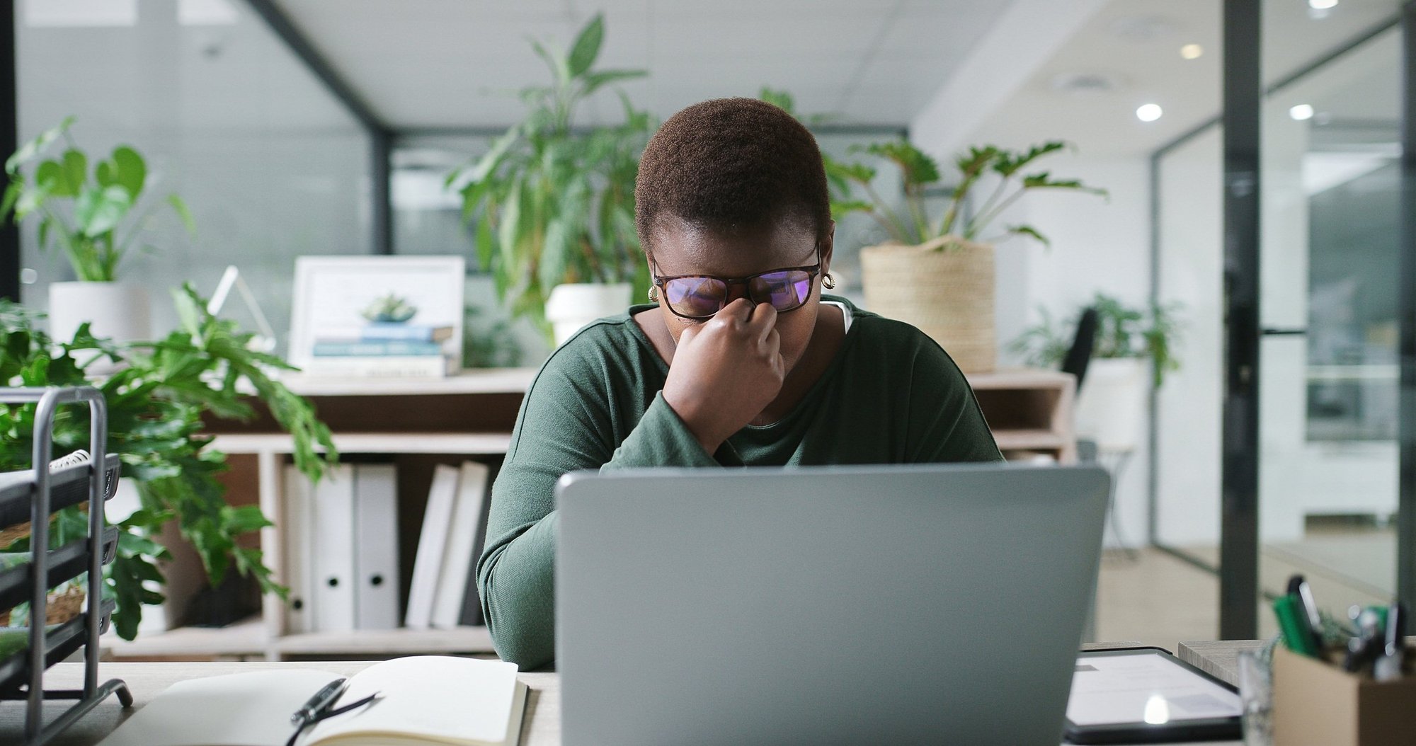 Stressed employee at a cluttered desk, head in hands, suggesting overwhelm and exhaustion, highlighting signs of workplace burnout.