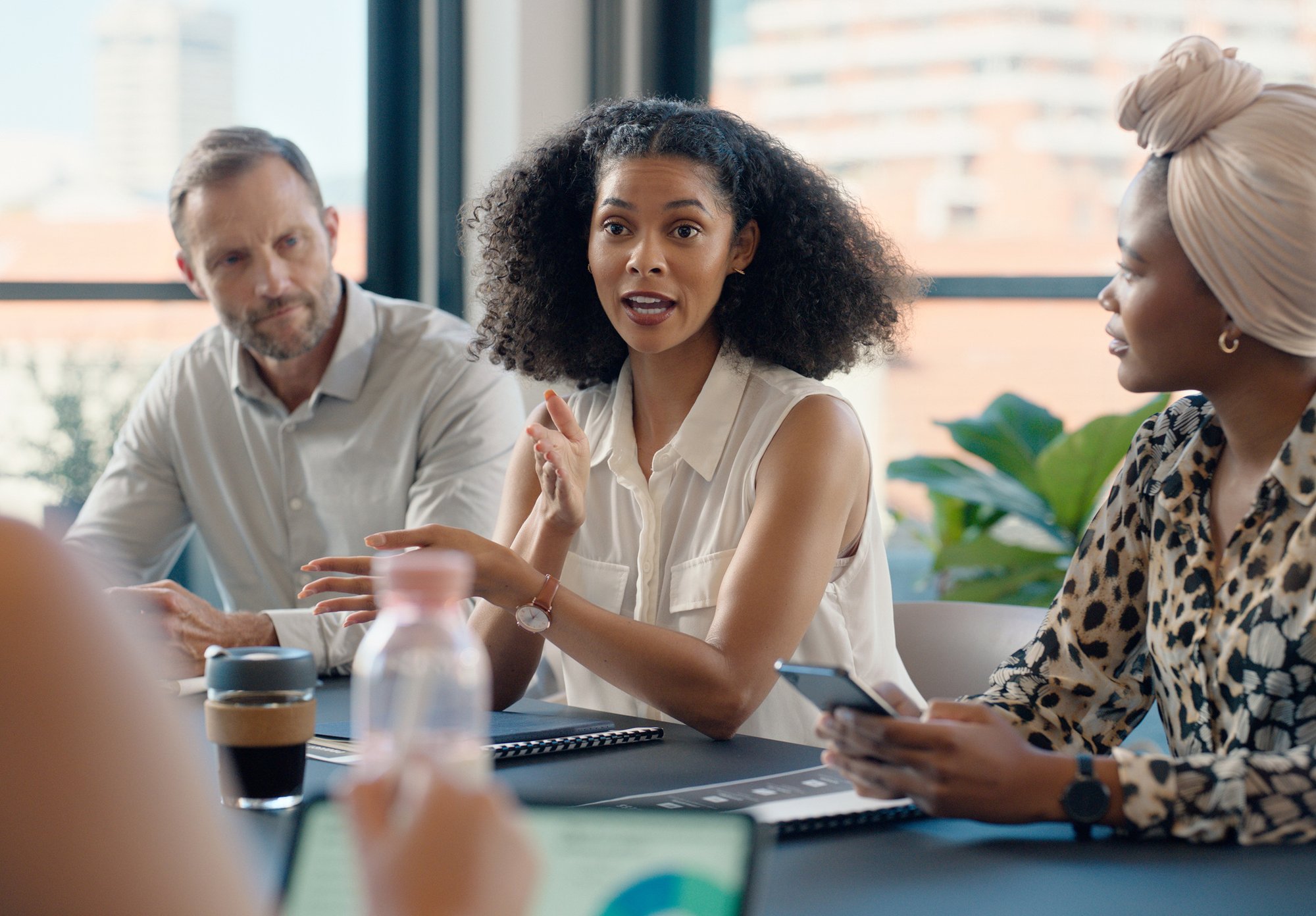 Woman speaking confidently while colleagues listen attentively in a modern meeting room.