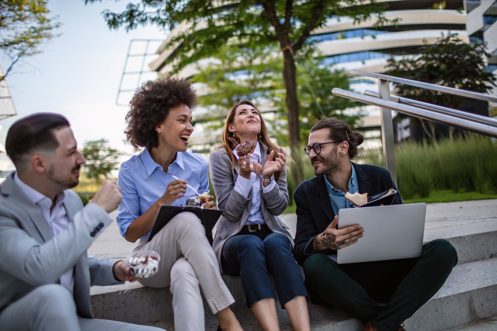 A group of four employees enjoying a laugh outside during lunch.